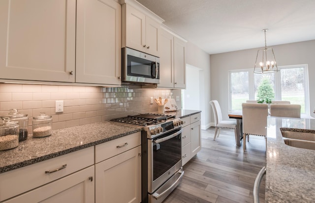 kitchen featuring decorative backsplash, light hardwood / wood-style flooring, stainless steel appliances, white cabinets, and stone countertops