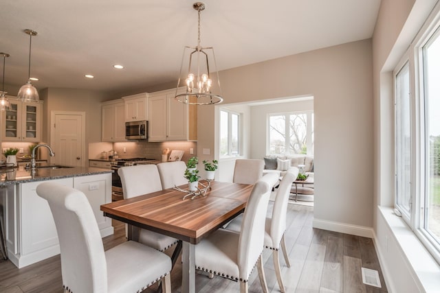 dining room featuring dark wood-type flooring, sink, a chandelier, and plenty of natural light