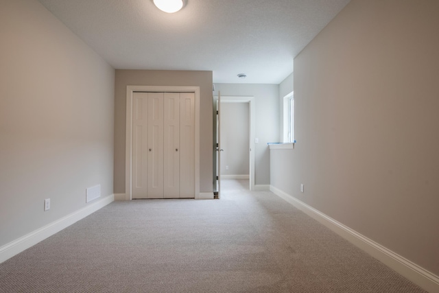 unfurnished bedroom featuring light colored carpet and a closet