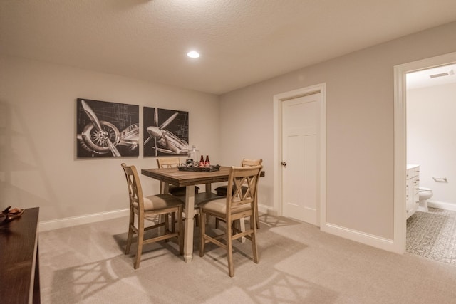 dining room with light carpet and a textured ceiling