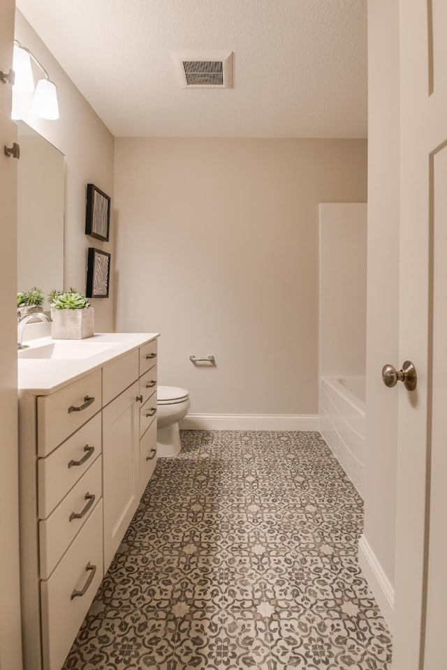 bathroom with tile patterned floors, a textured ceiling, toilet, and vanity