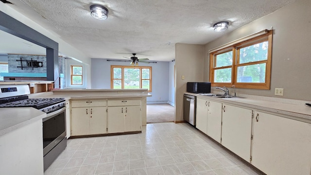 kitchen with a textured ceiling, plenty of natural light, kitchen peninsula, and stainless steel appliances