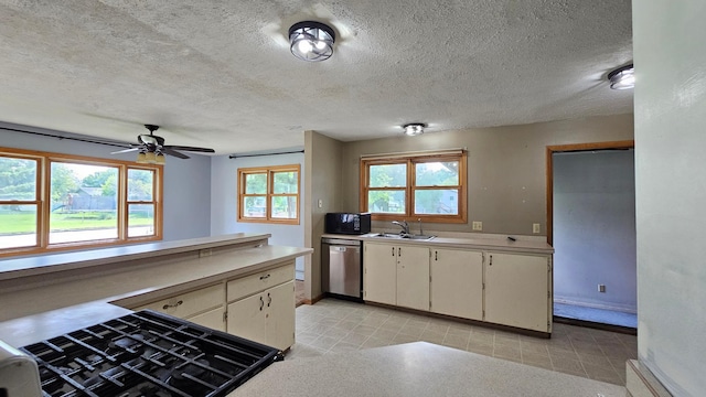 kitchen with cream cabinets, sink, stainless steel dishwasher, ceiling fan, and a textured ceiling