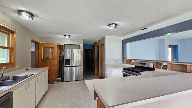 kitchen with a textured ceiling, stainless steel appliances, sink, and white cabinetry