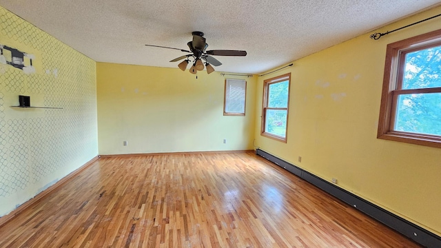 empty room featuring a textured ceiling, plenty of natural light, light hardwood / wood-style flooring, and ceiling fan