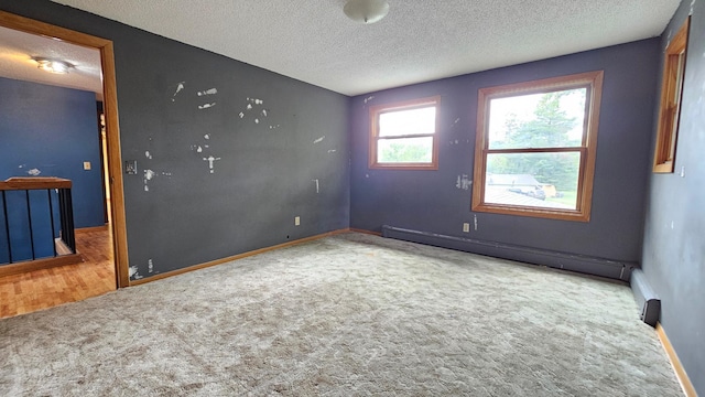 carpeted spare room with baseboard heating and a textured ceiling