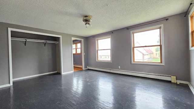 unfurnished bedroom with a closet, baseboard heating, dark hardwood / wood-style floors, and a textured ceiling