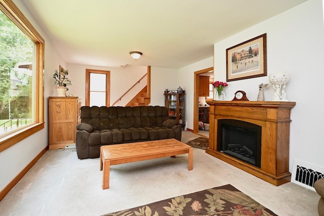 living room featuring visible vents, baseboards, stairs, light carpet, and a fireplace