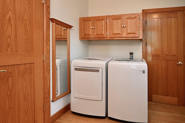 laundry room featuring light wood finished floors, baseboards, cabinet space, and washing machine and clothes dryer