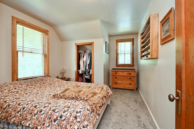 bedroom with a spacious closet, baseboards, light colored carpet, vaulted ceiling, and a closet