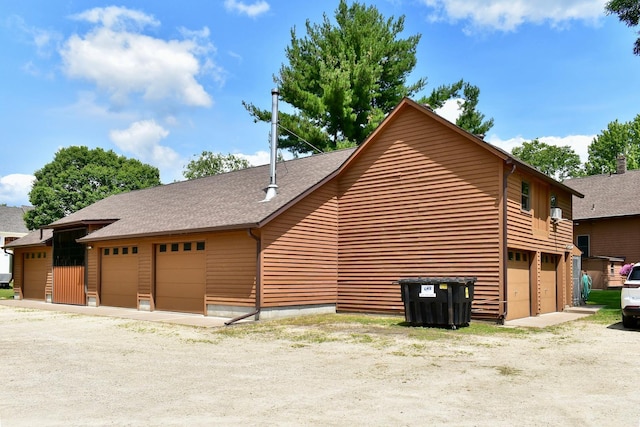 view of side of property with a garage and a shingled roof