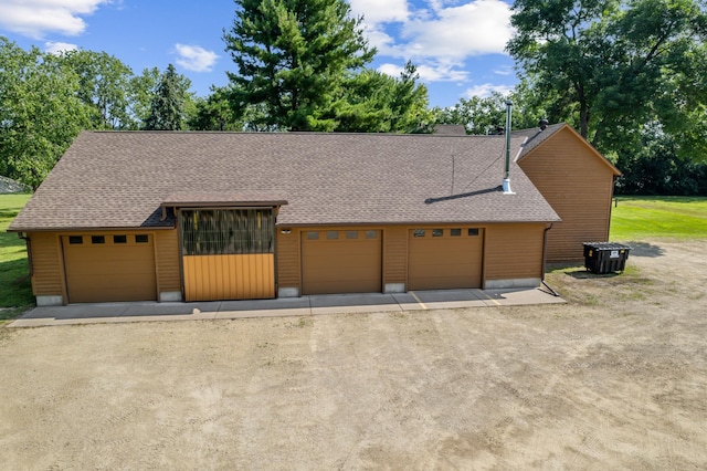 view of front of home featuring a garage, dirt driveway, and a shingled roof