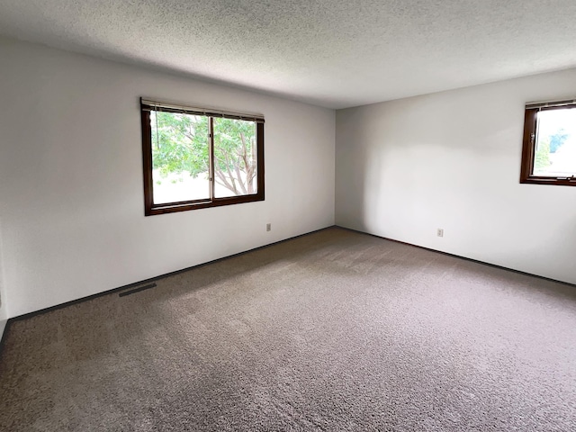 carpeted empty room with a textured ceiling