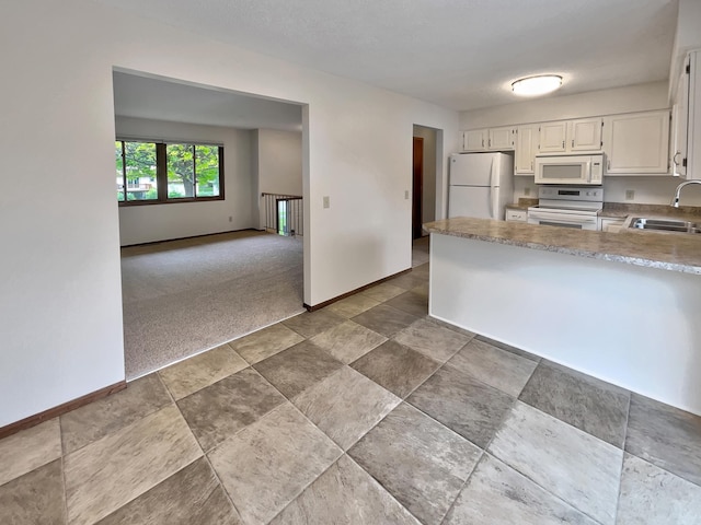 kitchen with sink, white cabinets, white appliances, and dark colored carpet