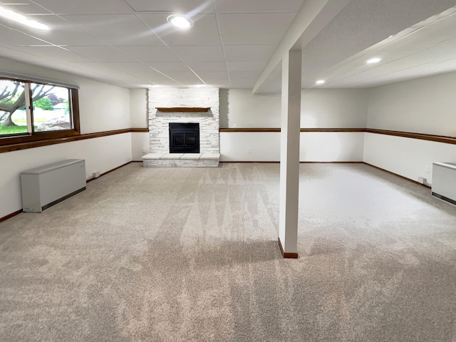 basement with light colored carpet, radiator heating unit, and a fireplace