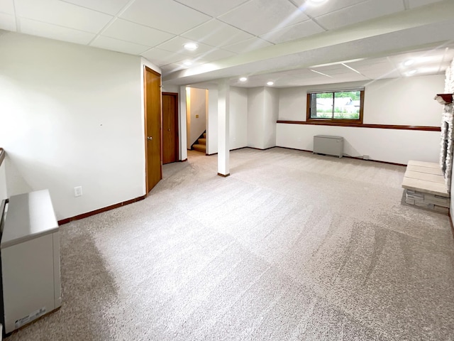 basement with a drop ceiling and light colored carpet