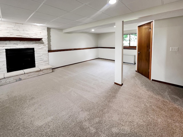 basement with a drop ceiling, a stone fireplace, and light colored carpet