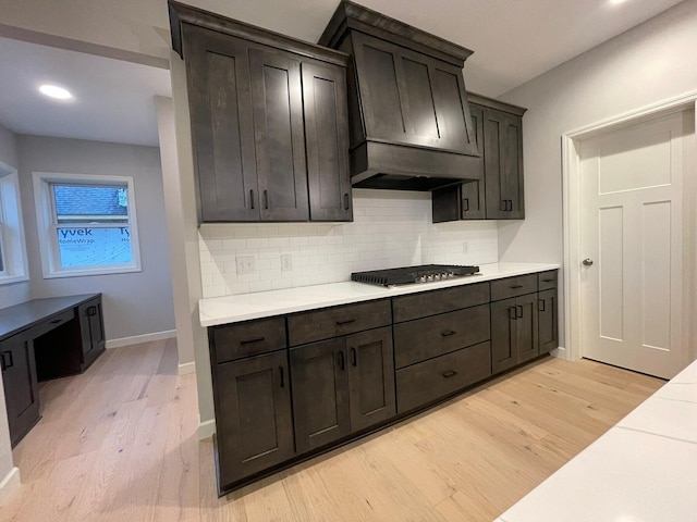 kitchen with light wood finished floors, light countertops, tasteful backsplash, and stainless steel gas stovetop