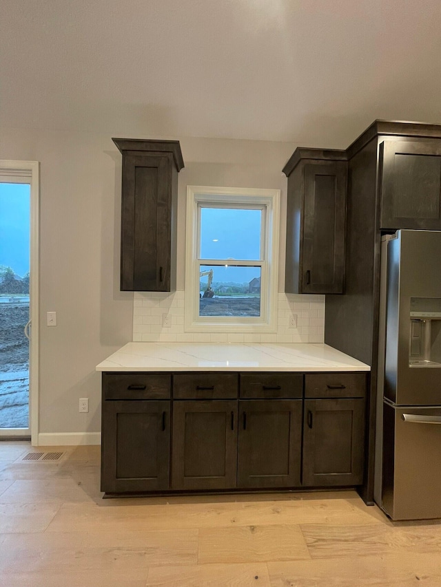 kitchen with tasteful backsplash, stainless steel refrigerator with ice dispenser, and dark brown cabinetry