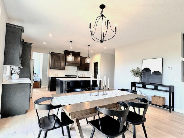 dining area featuring baseboards, light wood finished floors, recessed lighting, and a notable chandelier