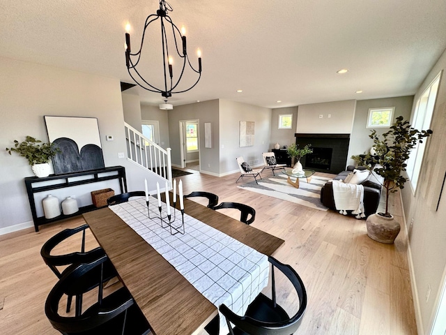 dining area with recessed lighting, a fireplace, baseboards, light wood-style floors, and stairway