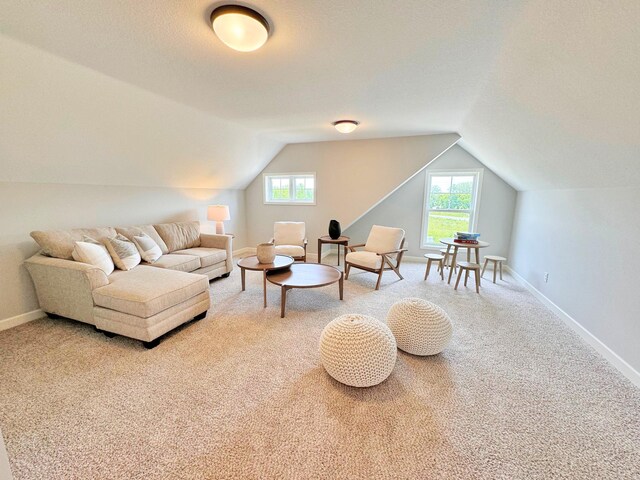 living area featuring carpet floors, vaulted ceiling, and a wealth of natural light