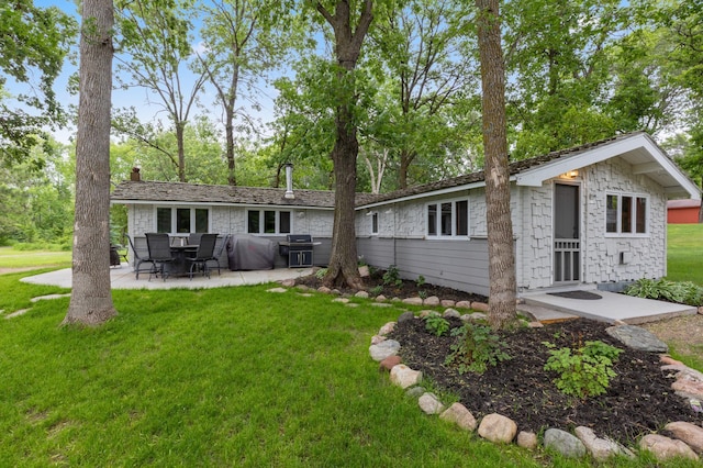 back of property with a lawn, a chimney, and a patio