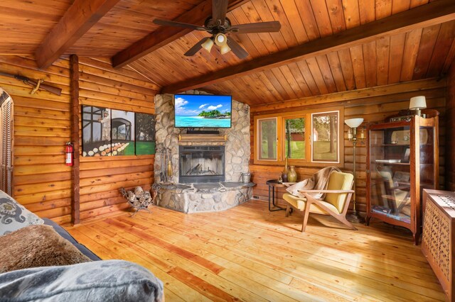 living room with light hardwood / wood-style floors, lofted ceiling with beams, a fireplace, wooden ceiling, and log walls