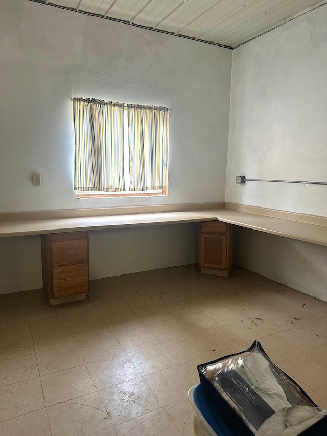 unfurnished office featuring built in desk and light tile patterned floors