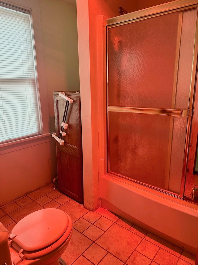 bathroom featuring toilet, combined bath / shower with glass door, and tile patterned flooring