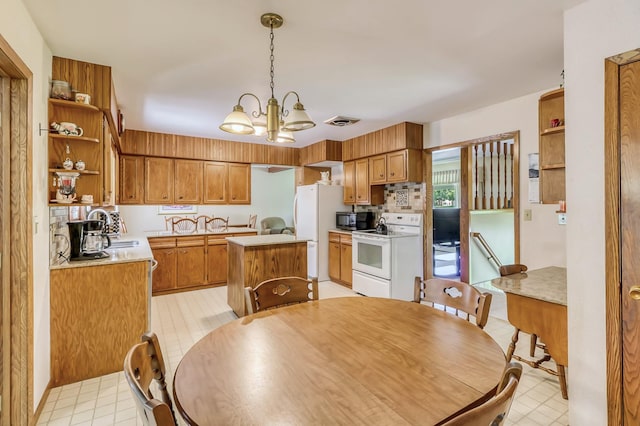 kitchen featuring a center island, white appliances, sink, decorative light fixtures, and a notable chandelier