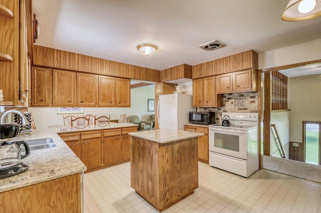 kitchen featuring white appliances, sink, decorative backsplash, light stone countertops, and a kitchen island