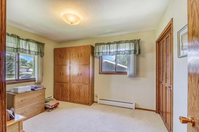 carpeted bedroom featuring multiple windows, a closet, and a baseboard heating unit