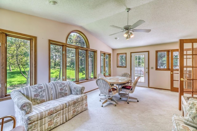 dining room featuring light carpet, vaulted ceiling, plenty of natural light, and ceiling fan