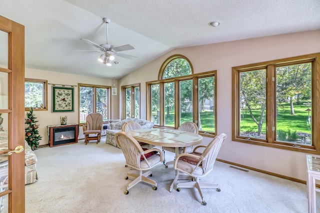 dining room featuring light colored carpet, a healthy amount of sunlight, and lofted ceiling