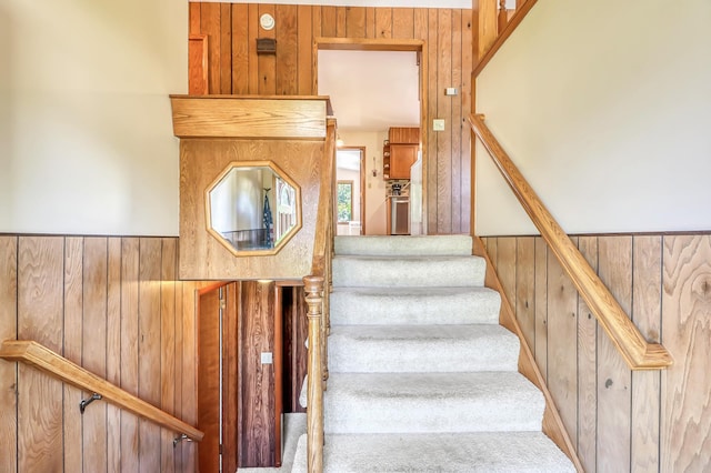 stairway with carpet flooring and wooden walls