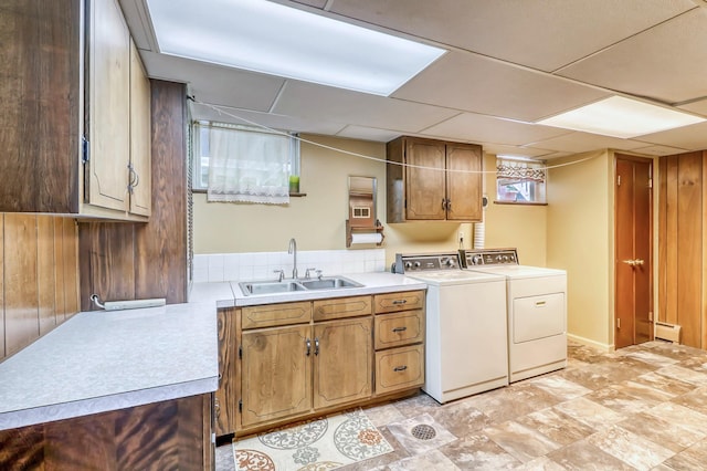 washroom with cabinets, washing machine and dryer, a baseboard heating unit, and sink