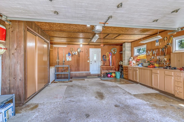 garage featuring a workshop area, wooden walls, and a garage door opener