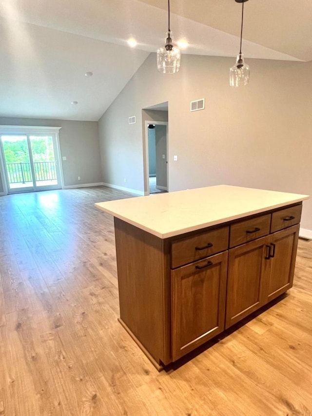 kitchen featuring light hardwood / wood-style floors, vaulted ceiling, an inviting chandelier, hanging light fixtures, and a center island