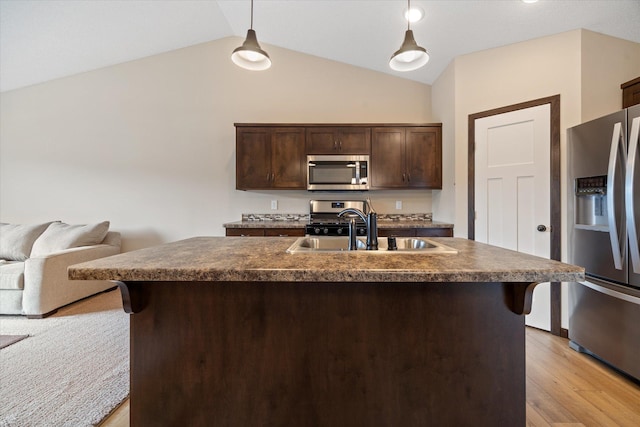 kitchen with hanging light fixtures, appliances with stainless steel finishes, a kitchen island with sink, and dark brown cabinetry