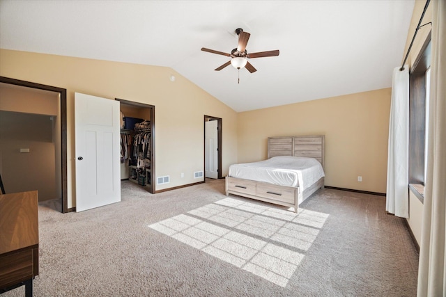 bedroom with lofted ceiling, a walk in closet, light carpet, and ceiling fan