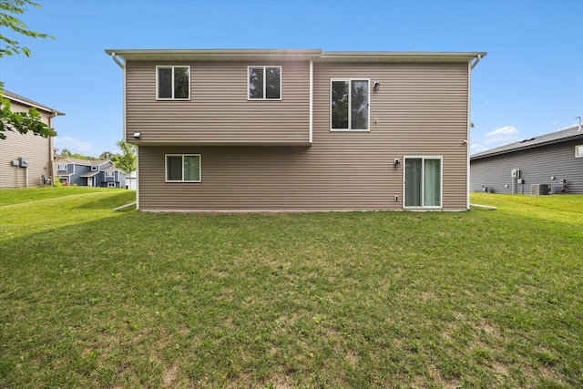 rear view of property featuring central AC and a lawn