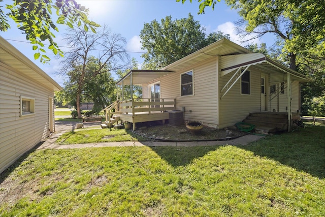 back of property featuring a wooden deck, a yard, and central AC