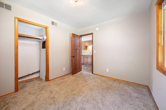 unfurnished bedroom with light carpet and a closet