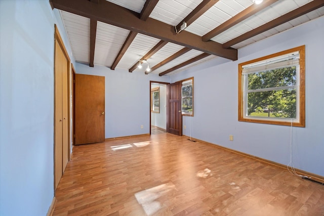 empty room featuring beamed ceiling, wood ceiling, and light hardwood / wood-style flooring