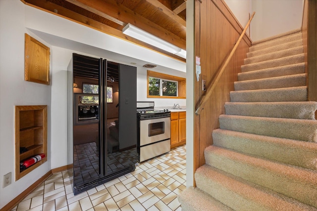 kitchen featuring electric stove, black refrigerator with ice dispenser, and beamed ceiling