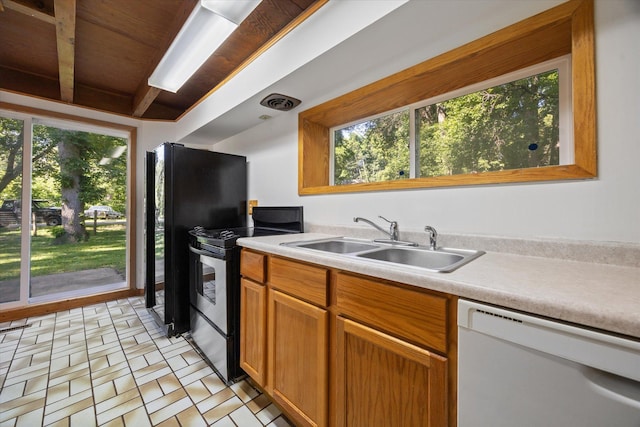 kitchen with electric stove, sink, black refrigerator, and dishwasher