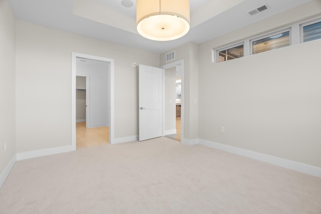 unfurnished bedroom featuring a walk in closet, light carpet, and a closet