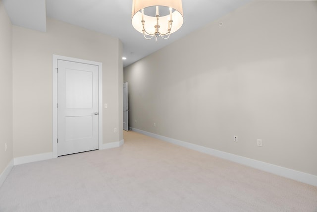 carpeted spare room featuring a chandelier