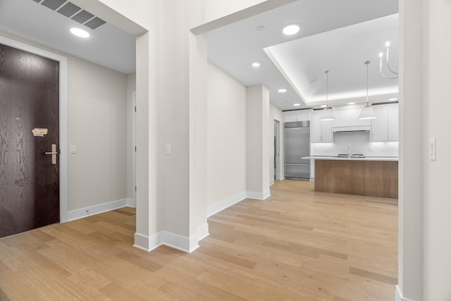 interior space featuring a tray ceiling, sink, and light hardwood / wood-style floors